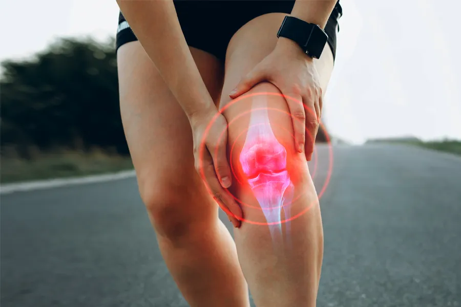 ACL-Tears-Clinic A woman running on the road holds her knee in pain. Schedule treatment for ACL tears from Lux Hormones & Health Wellness in San Diego.