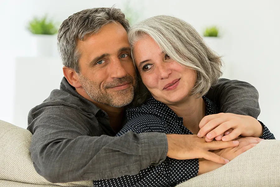 Bioidentical-Hormone-Replacement-Therapy-Clinic-6 A healthy, happy middle-aged couple sitting on their couch. Schedule bioidentical hormone replacement pellet therapy from Lux Hormones & Health Wellness in San Diego.