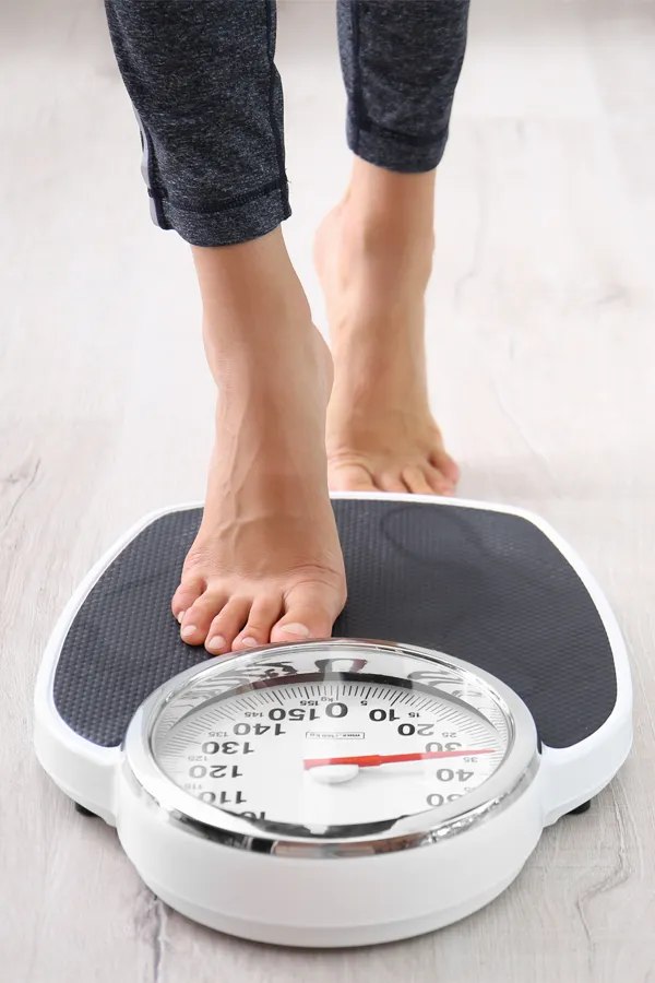 Obesity-Treatment Close up of feet stepping onto a scale. Receive expert functional medicine for obesity treatment by Lux Hormones & Health Wellness in San Diego.