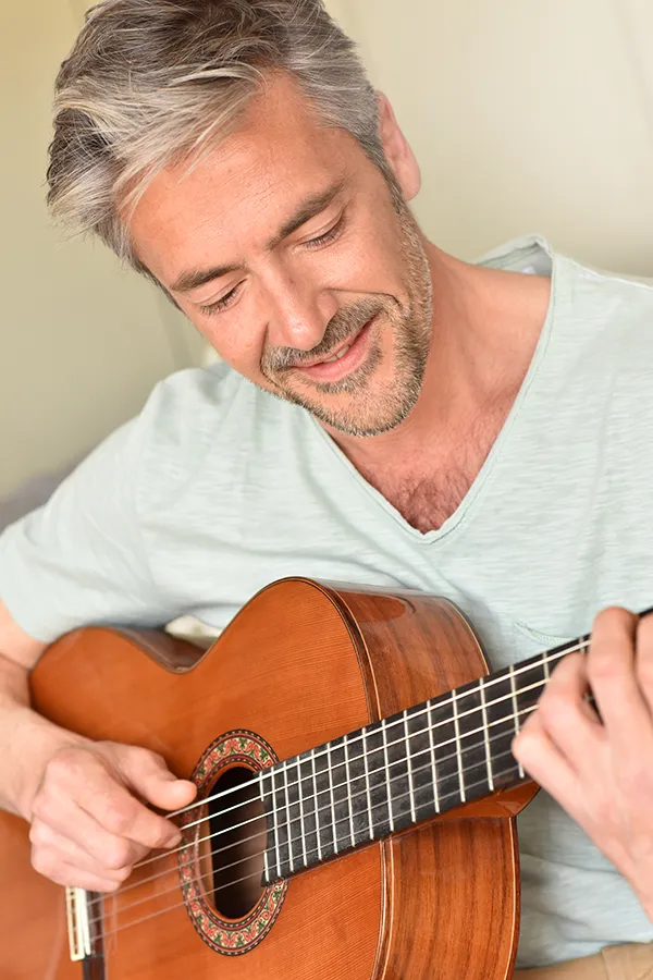 Osteoarthritis-Treatment A middle-aged man happily plays guitar. Get osteoarthritis treatment from Lux Hormones & Health Wellness in San Diego.