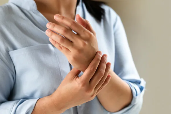 Rheumatoid-Arthritis-Clinic Close up of a woman in a blue blouse rubbing her wrist. Get rheumatoid arthritis treatment from Lux Hormones & Health Wellness in San Diego.