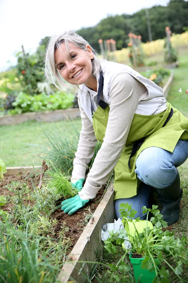 Rheumatoid-Arthritis-Treatment A mature woman bending down working on her garden happily after successful rheumatoid arthritis treatment from Lux Hormones & Health Wellness in San Diego.