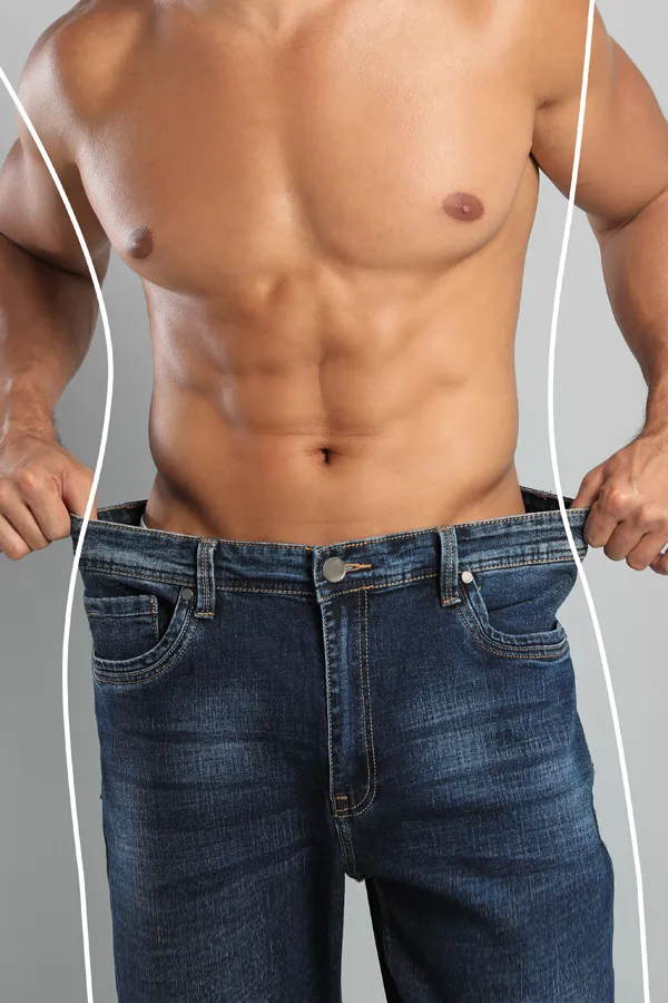 Semaglutide-Weight-Loss-Treatment A strong shirtless man in jeans holds the waistlines of his too-big jeans to show the success of semaglutide weight loss from Lux Hormones & Health Wellness in San Diego.
