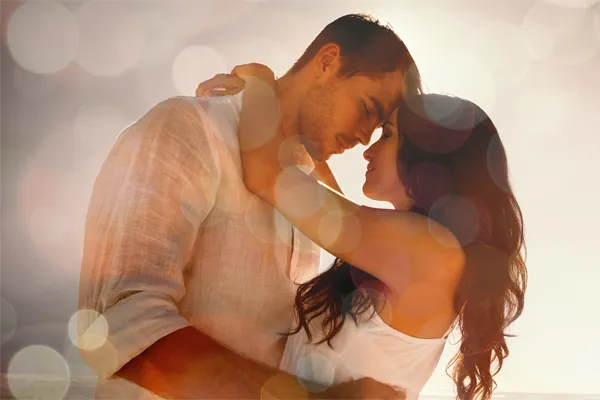 Sexual-Wellness-for-Women-and-Men-Doctor A couple in linen shirts standing in a sparkling light embraces each other with their foreheads touching and eyes closed, happy with their sexual wellness treatments from Lux Hormones & Health Wellness in San Diego.