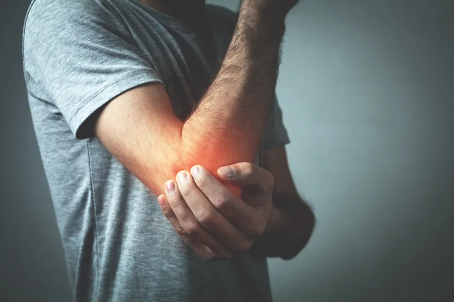 Tennis-Elbow-Clinic A man holds his elbow in pain. Schedule tennis elbow treatment from Lux Hormones & Health Wellness in San Diego.