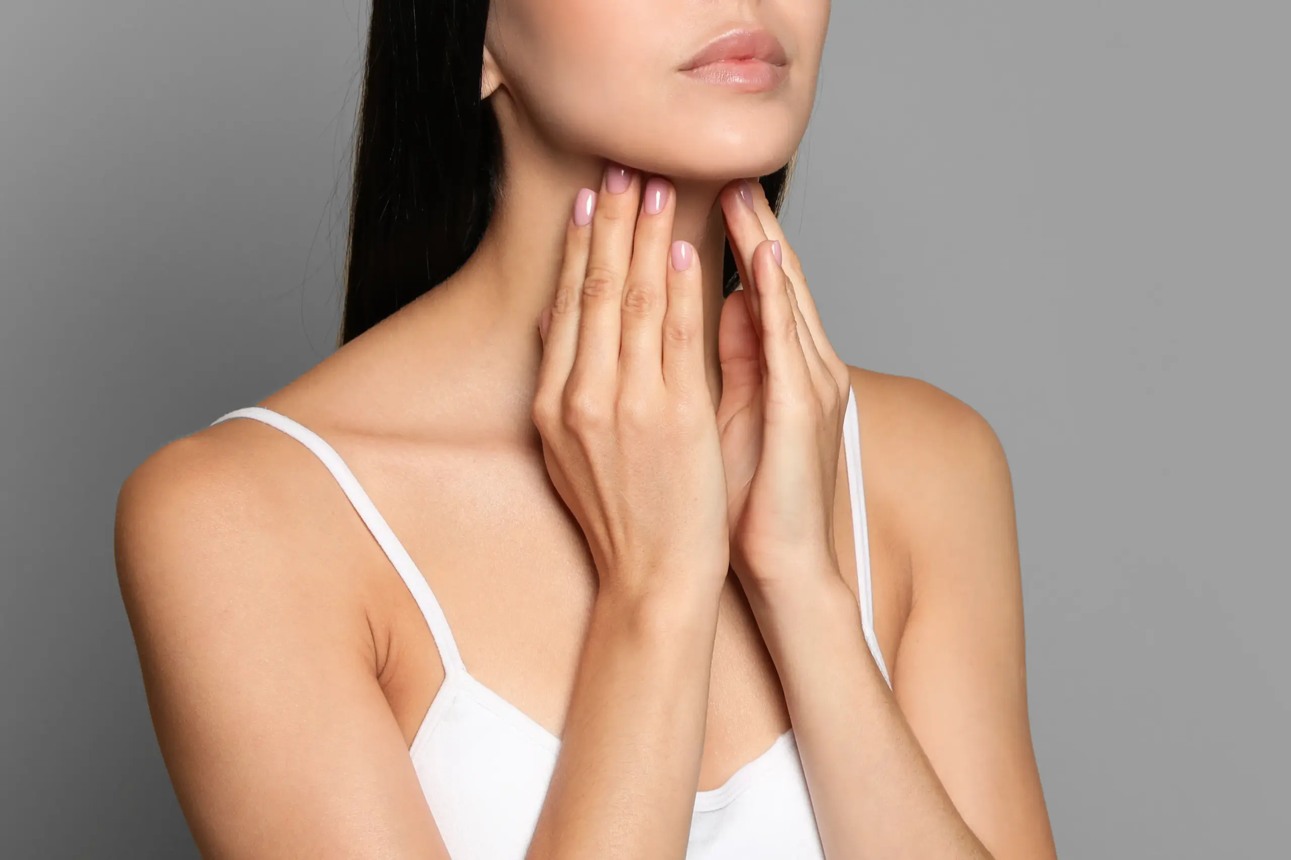 Thyroid-Doctor A woman in a white tank top touches her neck looking for signs of thyroid disorder. Get help for thyroid disorders from Lux Hormones & Health Wellness in San Diego.